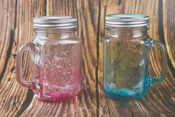 Pink and blue Mason jar isolated on wooden background 