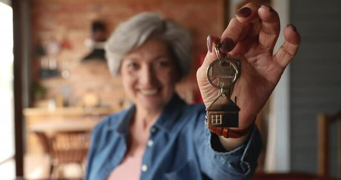 Close up view happy homeowner elderly woman holding bunch of keys. Concept of bank loan for older citizen, real-estate female agent offering affordable house, moving relocating day to new own dwelling