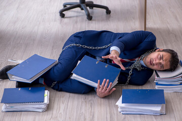 Chained male employee unhappy with excessive work in the office