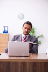 Young male employee reading book in the office