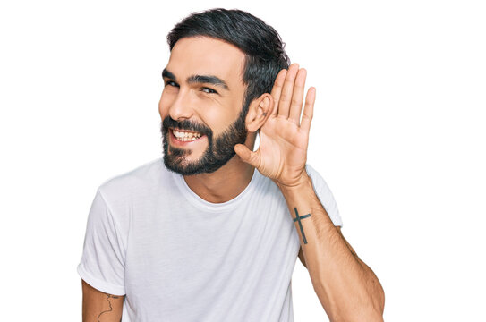 Young hispanic man wearing casual white t shirt smiling with hand over ear listening an hearing to rumor or gossip. deafness concept.