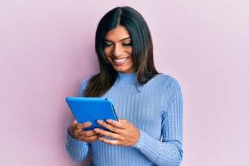 Young latin transsexual transgender woman using touchpad device smiling with a happy and cool smile...
