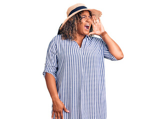 Young african american plus size woman wearing summer hat shouting and screaming loud to side with hand on mouth. communication concept.