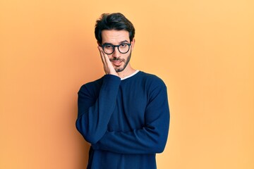 Fototapeta premium Young hispanic man wearing casual clothes and glasses thinking looking tired and bored with depression problems with crossed arms.