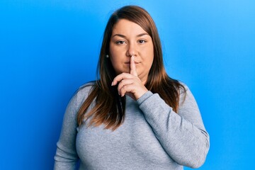 Beautiful brunette plus size woman wearing casual clothes asking to be quiet with finger on lips. silence and secret concept.