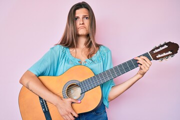 Fototapeta premium Beautiful caucasian woman playing classical guitar depressed and worry for distress, crying angry and afraid. sad expression.