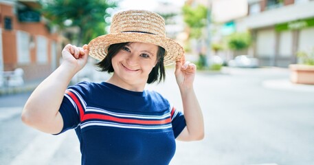 Beautiful brunette woman with down syndrome wearing a summer hat at the town on a sunny day