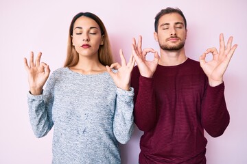 Beautiful couple wearing casual clothes relax and smiling with eyes closed doing meditation gesture with fingers. yoga concept.