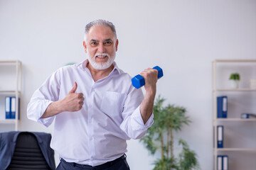 Aged male employee doing physical exercises during break