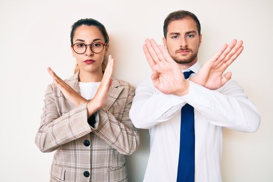 Beautiful couple wearing business clothes rejection expression crossing arms doing negative sign, angry face