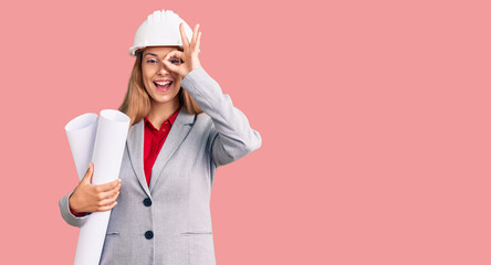 Beautiful young woman wearing architect hardhat holding build project smiling happy doing ok sign with hand on eye looking through fingers