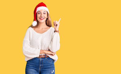 Beautiful young woman wearing christmas hat smiling happy pointing with hand and finger to the side
