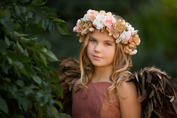 Portrait of young girl with wings and flower crown as angel or fairy