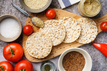 Crispy puffed rice cakes on table hummus spread and tomato vegetables and sesame seeds on the table - top view on healthy vegetarian or vegan breakfast gluten free