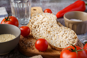 Crispy puffed rice cakes on table hummus spread and tomato vegetables and sesame seeds on the table - close up view on healthy vegetarian or vegan breakfast gluten free