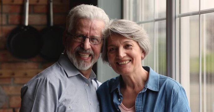 Head shot 65s spouses looking at camera having wide white toothy smile, dentures services for older patients clinic ad. Wedding anniversary celebration, eternal love, affection couple portrait concept
