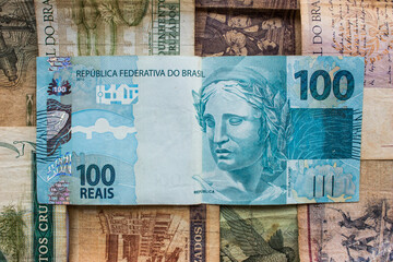One hundred reais. BTL brazilian blue banknote on top of former national currencies
