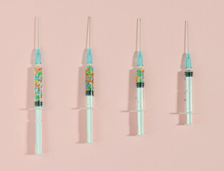 on a pink background arranged 4 syringes with decorated chocolate colorful sprinklers. the concept...