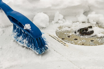 Blue removal brush removes snow from the airplane wing near the gas station neck on a winter day, snowfall, non-flying weather, close-up.