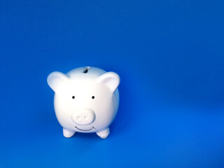 white piggy bank on blue background, financial and saving money for investment concept