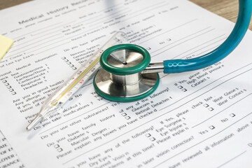 Close-up of a stethoscope and mercury thermometer on a medical history. Medical concept