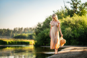 Fototapeta na wymiar A model in a translucent dress walks along the river