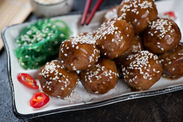 Close-up of pan fried meatballs in teriyaki sauce topped with sesame, selective focus