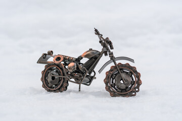 Fototapeta na wymiar Metal model toy sports motorcycle stands on a snowy road, white background
