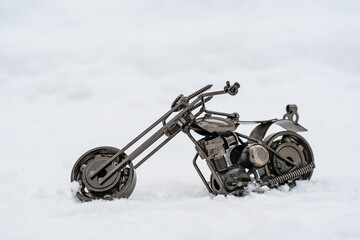 Fototapeta na wymiar Metal model of a road motorcycle stands on a snowy road, white background
