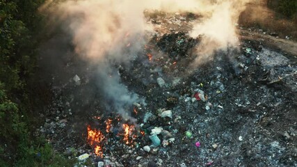 Garbage and fire burn in landfill. Also call trash, waste, rubbish. Destruction with combustion, heat, flame. Occurs smoke, toxic cause of air pollution, environmental damage and global warming.
