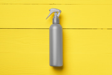 Gray cosmetic bottle on yellow wooden background