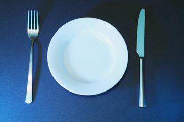 Empty white plate with knife and fork.