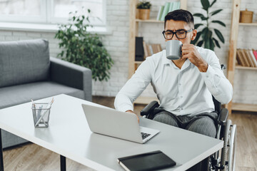 Disabled young businessman drinking coffee at his working table