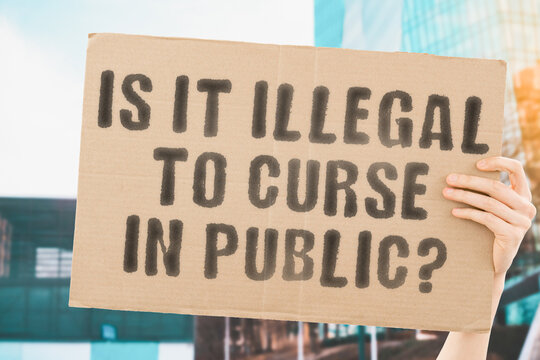 The question " Is it legal to curse in public? " on a banner in men's hand with blurred background. Conflict. Rules. Communication. Rights. Illegal. Violence. Offensive
