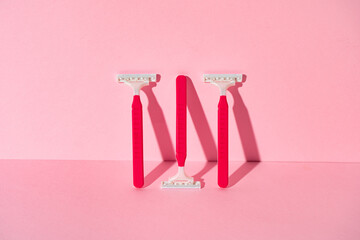 Pink disposable razors on pink background, copy space