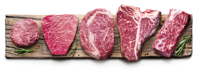 Different raw beef steaks on the wooden board on white background. Top view.