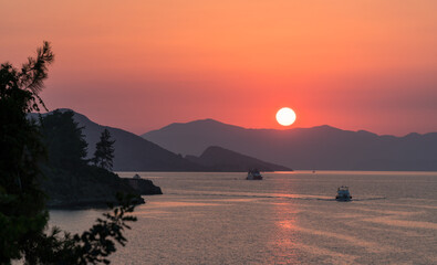 Calm sea and sunset. Sun is setting behind the hills on the horizont.  Beautiful nature background.