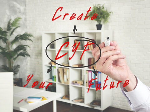 Written phrase CYF Create Your Future . Hand holding marker for writing isolated on background.