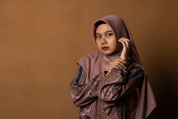 Fashion portrait of young beautiful asian muslim woman with wearing hijab isolated on gold background.