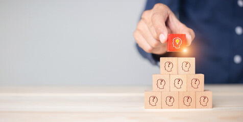 Hand business picked wooden cube block with head human symbol and light bulb icon  creative idea concept.