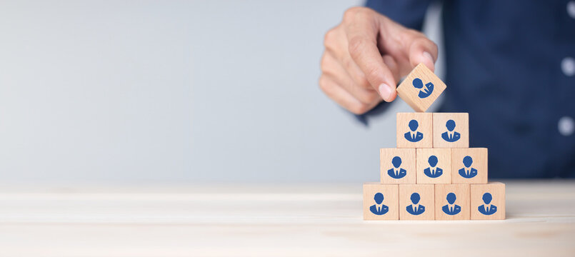 Concept of human resource management and recruitment business Hand put wood cube block on top pyramid To business success concept.