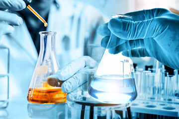 hand of scientist holding flask with lab glassware and test tubes in chemical laboratory...