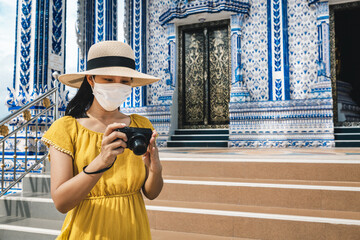 New normal travel of traveler asian woman with mask and camera sightseeing in temple Thailand