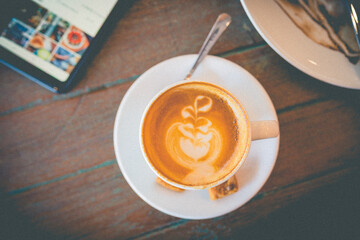 Latte hot coffee with foam milk art on a wooden table