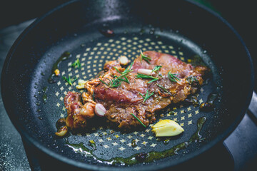Cooked beef steak with rosemary and garlic inside iron skillet - 408016841