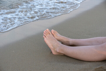 Girls' feet on the sand. Near the surf line.