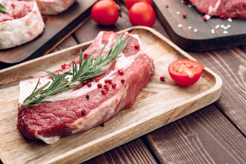 Raw beef steak with rosemary and spices on wooden board