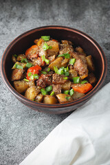 Stewed vegetables with spices in an earthen bowl on a dark gray slate or stone background. View from above.