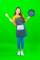 Portrait beautiful young asian woman wear apron with action on green background