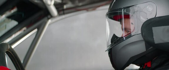 CU portrait of sports car driver closing helmet visor, starting a race on a speedway. Shot with 2x anamorphic lens
